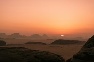 the sun is setting over a desert landscape cloud